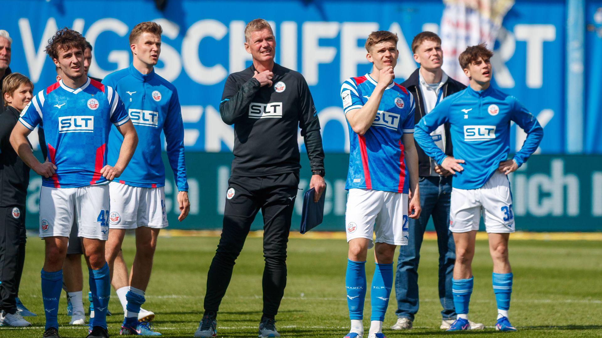 Spieler und Betreuer von Rostock stehen nach dem letzten Heimspiel vor der Fankurve