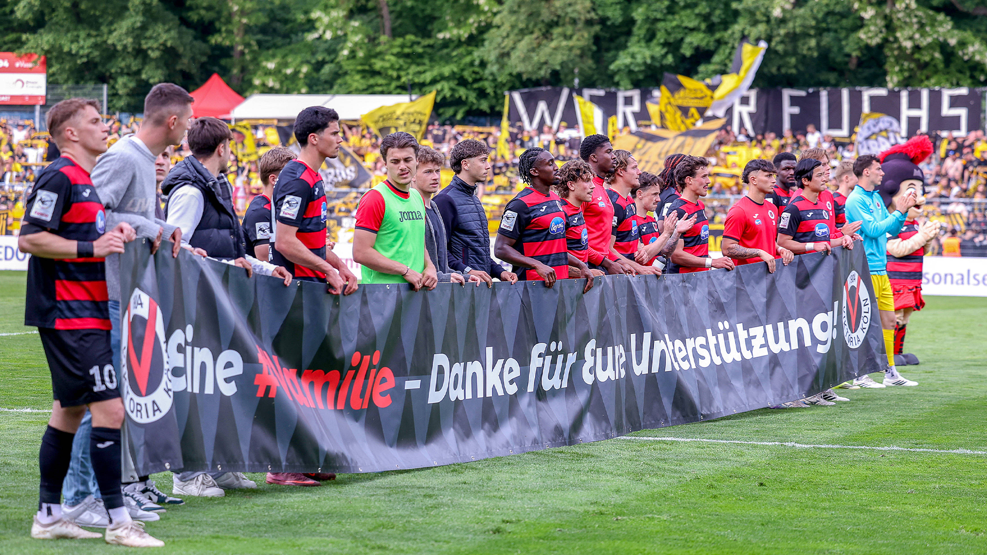 Die Mannschaft von Viktoria Köln mit einem Banner nach dem letzten Heimspiel der Saison 2025/26