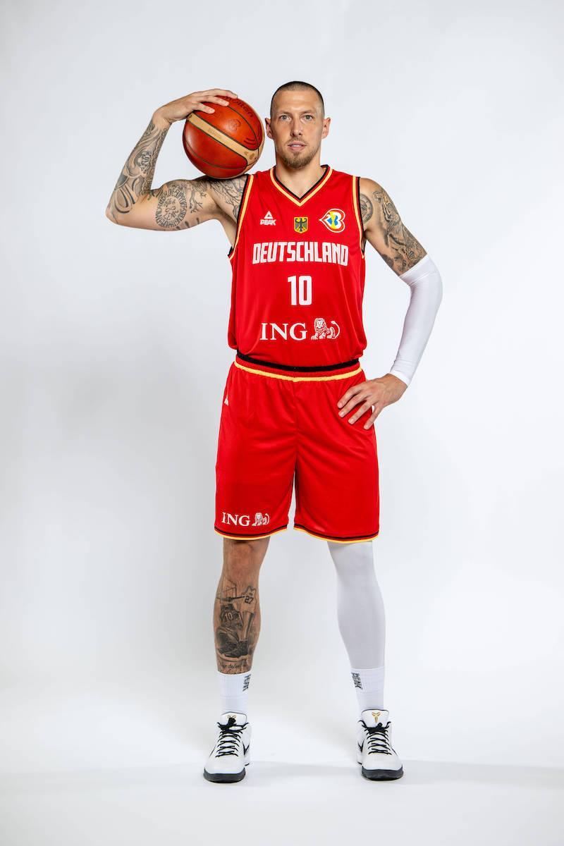 Daniel Theis während einem Fotoshooting. Auf der Rechetn Schulter hält Theis einen Basketball.