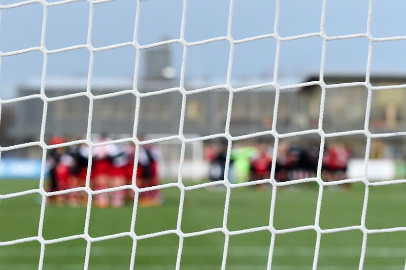 Aufnahme des Stadions durch das Tornetz. Durch das Netz sind die Teams im Mannschaftskreis vor dem Spiel zu sehen.