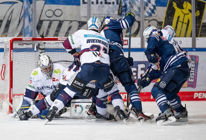 Spieler des EHC Red Bull München und der Eisbären Berlin im Duell um den Puck vor dem Münchner Tor.