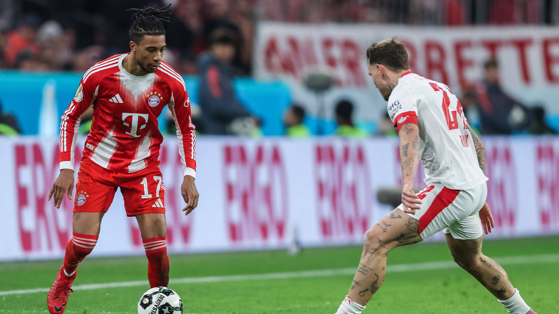Tottenham-Spieler Heung-Min Son beim Dribbling gegen Münchens Josip Stanišić während eines Spiels vor jubelndem Publikum.